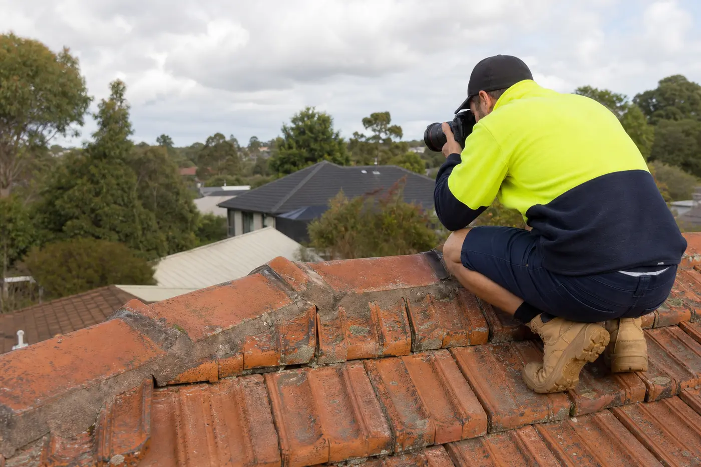 Roofer inspecting the ridge capping and flashings on a terracotta tile roof in Melbourne's northern suburbs