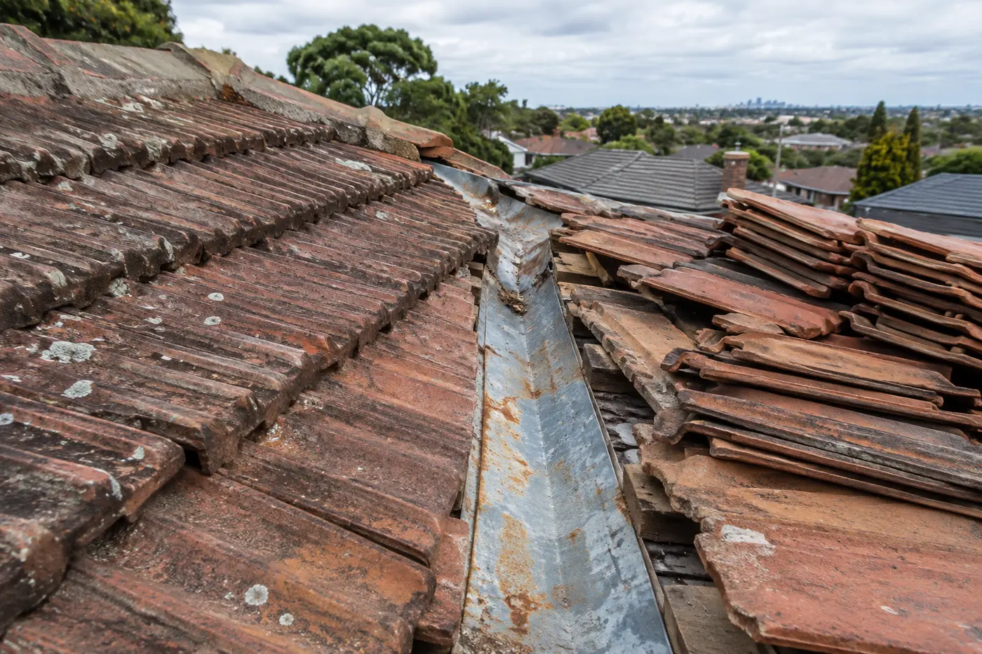 Rusted valley iron exposed between two slopes of terracotta tiles on a northern Melbourne bungalow